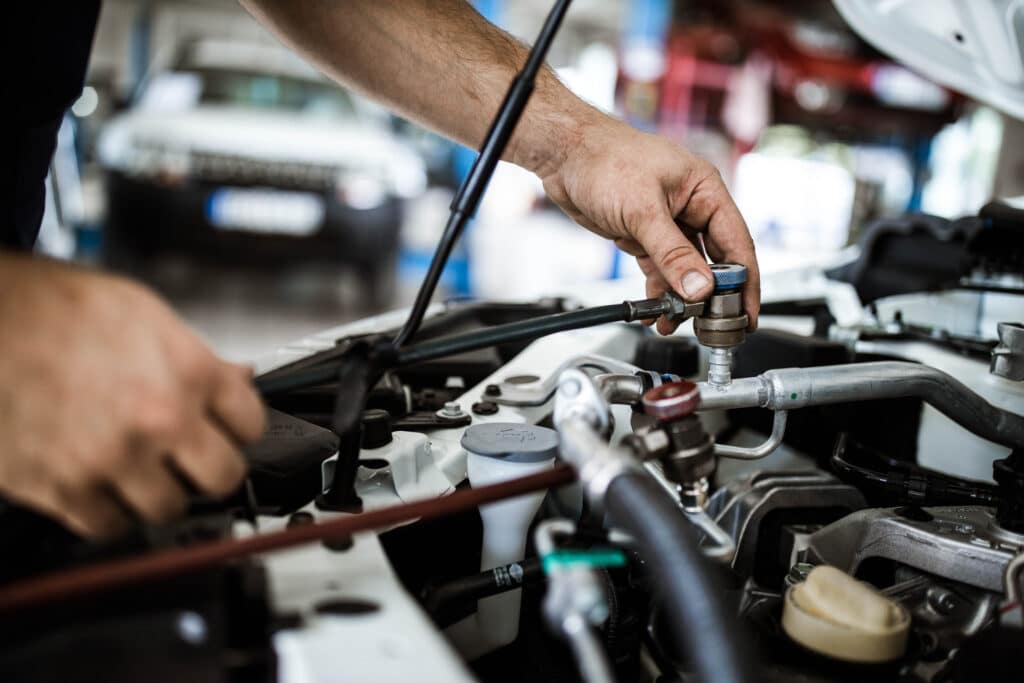 Close up of unrecognizable car mechanic recharging AC in a car.