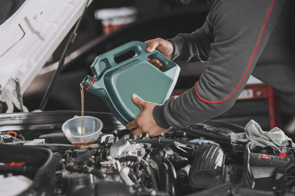 Pouring oil to car engine.