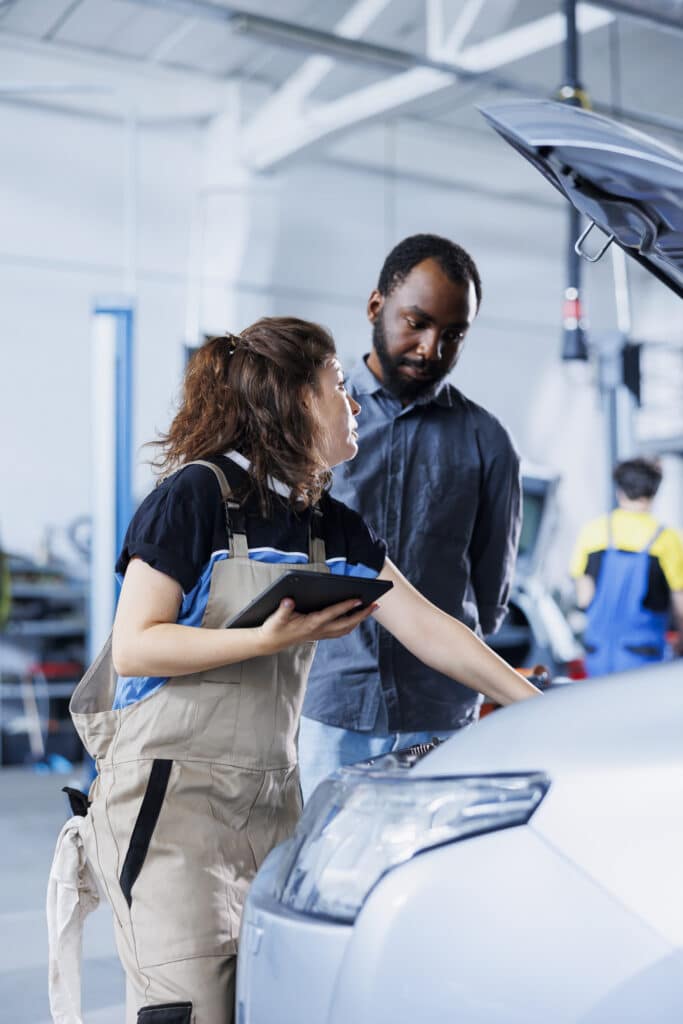 Mechanic in car service ordering new ignition system for damaged vehicle using tablet.