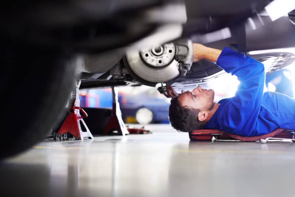 A car mechanic working on the underside of a car